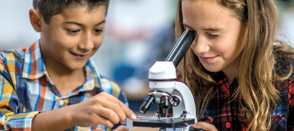Schülerin und Schüler mit Mikroskop